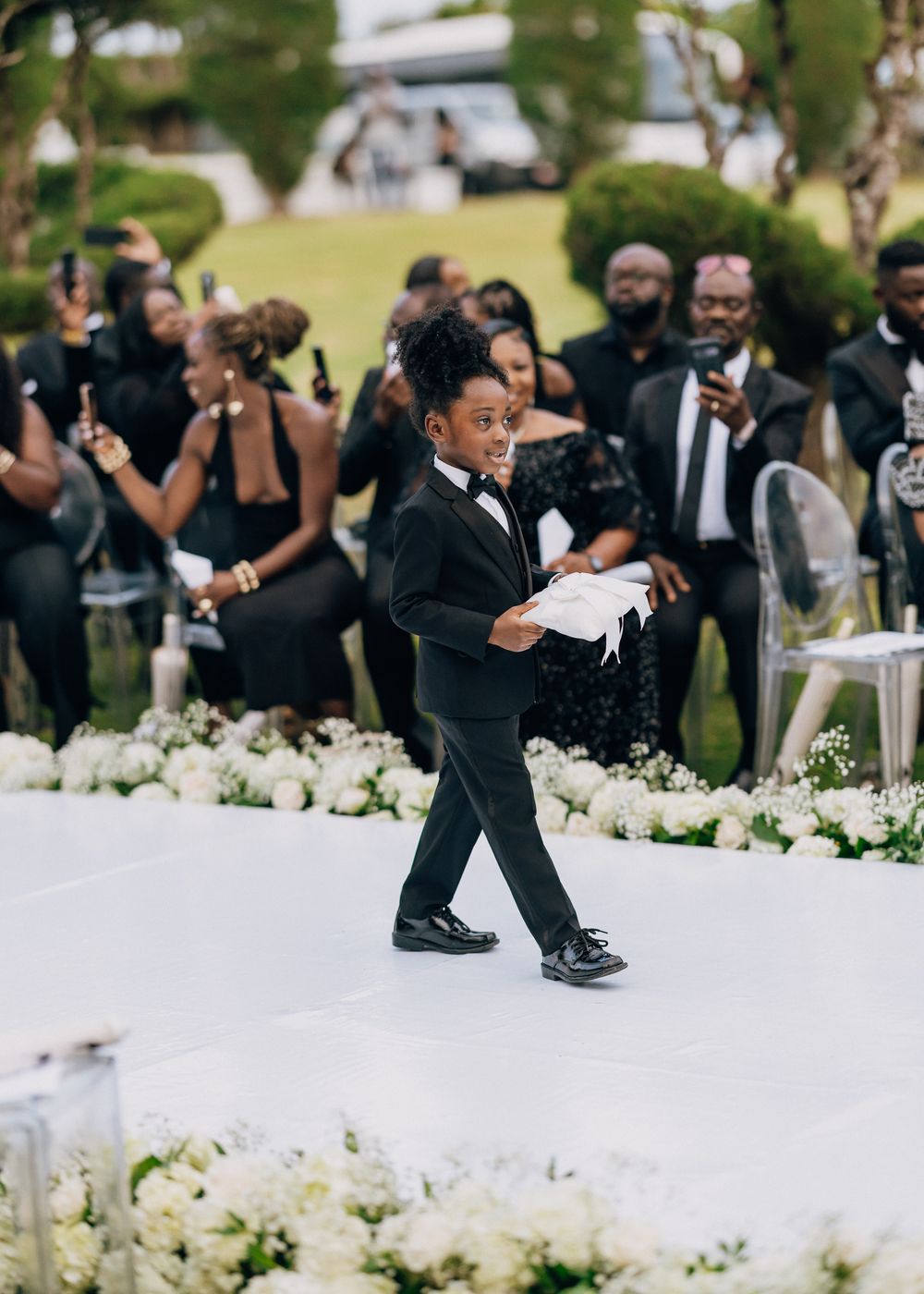 Wedding guests dance and celebrate at an outdoor reception with elegant white floral decorations.