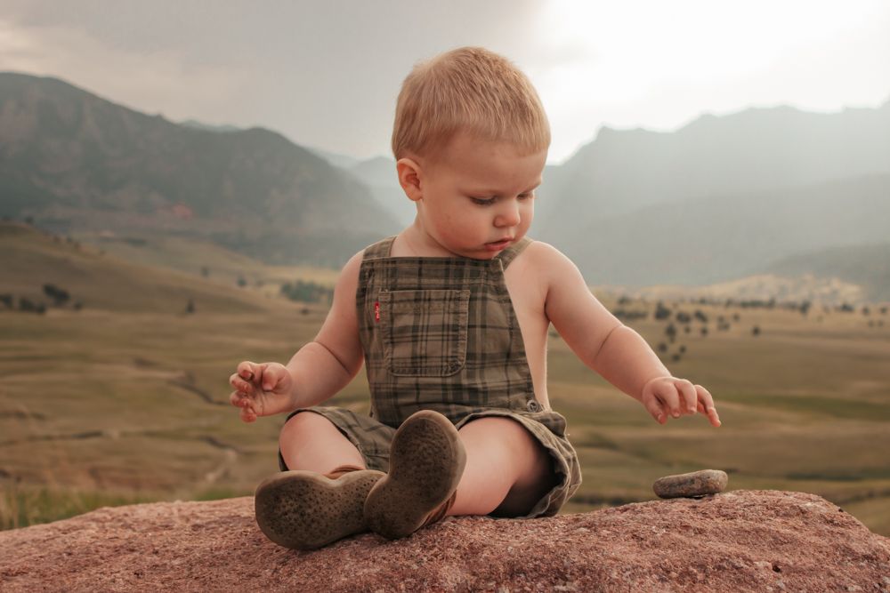 A young child in a brown shirt looks thoughtfully into the distance against a desert landscape background | Westminster Family Photographer