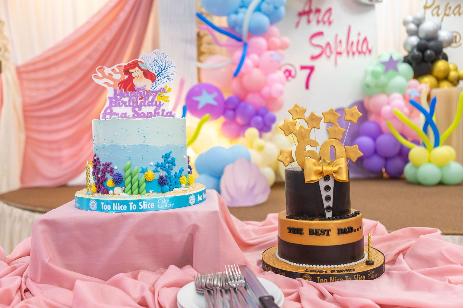 Colorful birthday party dessert table with balloons, cake and pastel pink decorations.