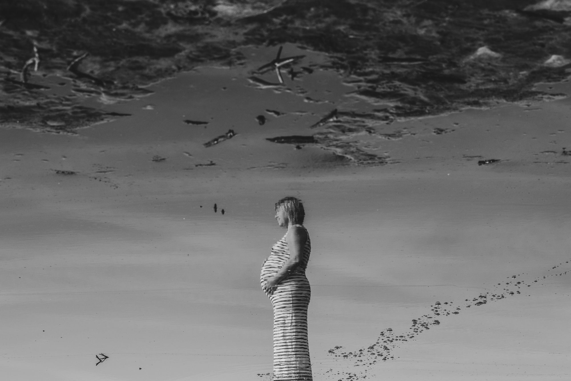 Artistiek zwangerschapsportret met een vrouw weerspiegeld in water, een creatief en rustig moment gefotografeerd in de provincie Antwerpen.
