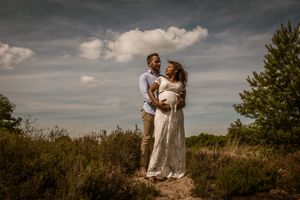 Zwangere vrouw en haar partner in de natuur, een teder en stijlvol moment dat de kracht van verwachting toont in de provincie Antwerpen.