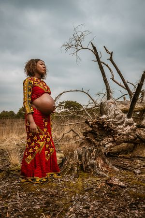 Natuurportret van een zwangere vrouw in een traditionele jurk, een rustig en waardig moment uit een zwangerschapsreportage in Antwerpen.