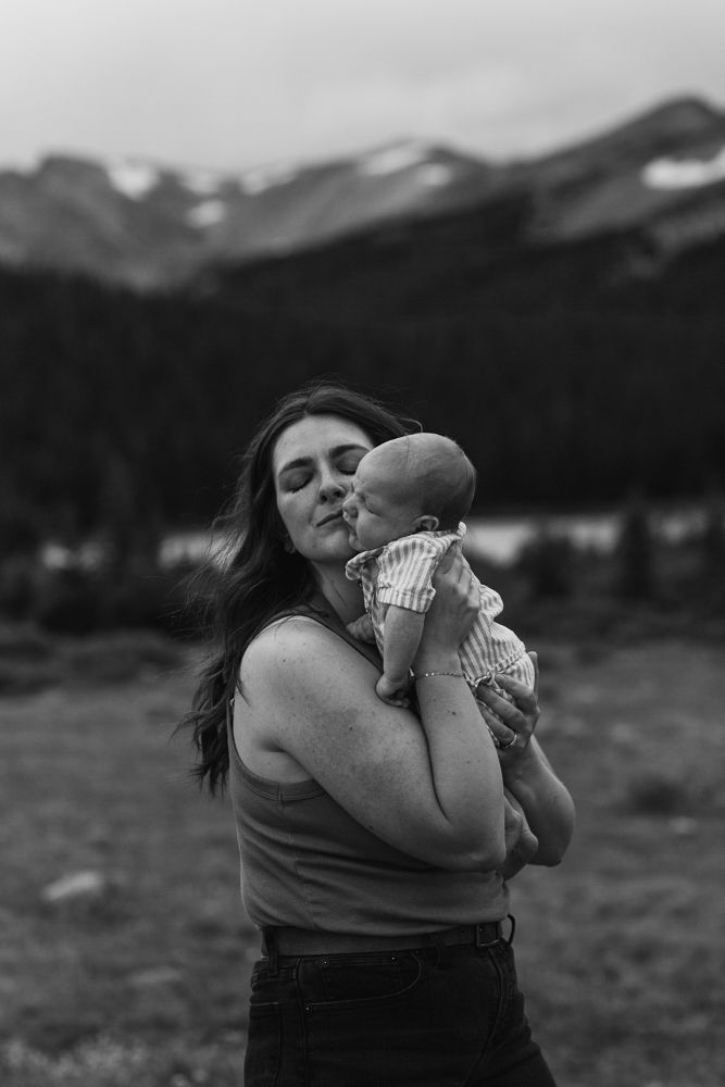 Black and white photo sequence showing someone blowing a dandelion in a mountain meadow with peaks in background.