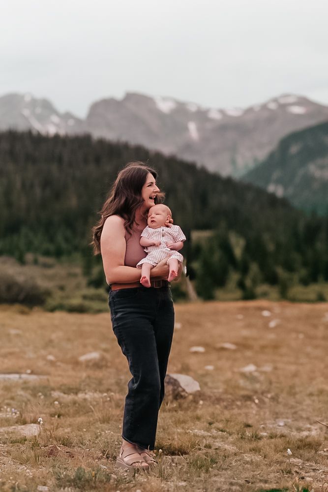A family enjoys a scenic mountain meadow with snow-capped peaks in the background during golden hour.