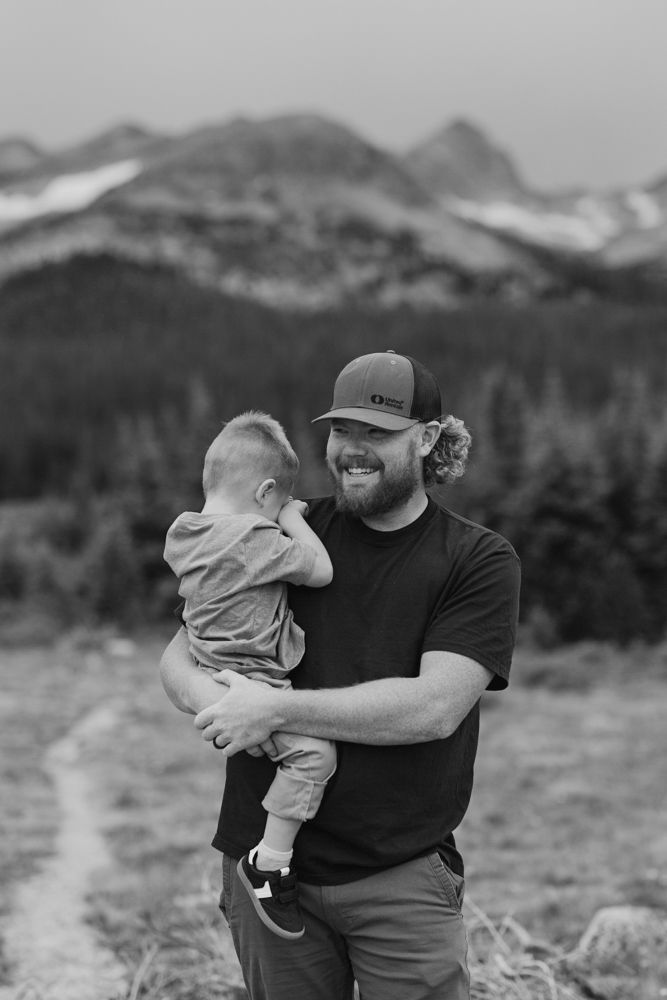 Black and white photo sequence showing a parent and child sharing playful moments against a mountain landscape backdrop.