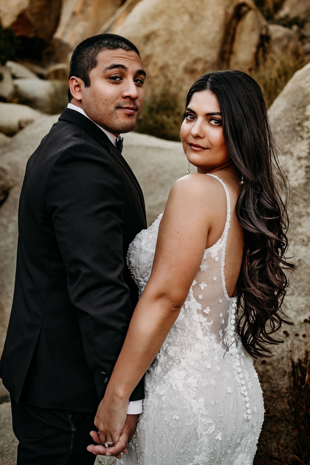 Candid wedding moments captured against desert landscape with natural stone backdrop.