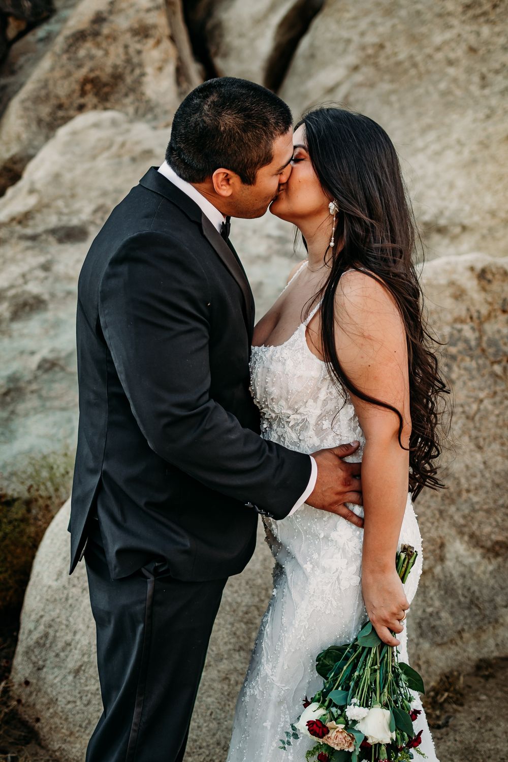 Romantic wedding portraits showcase tender moments against natural rock formations.