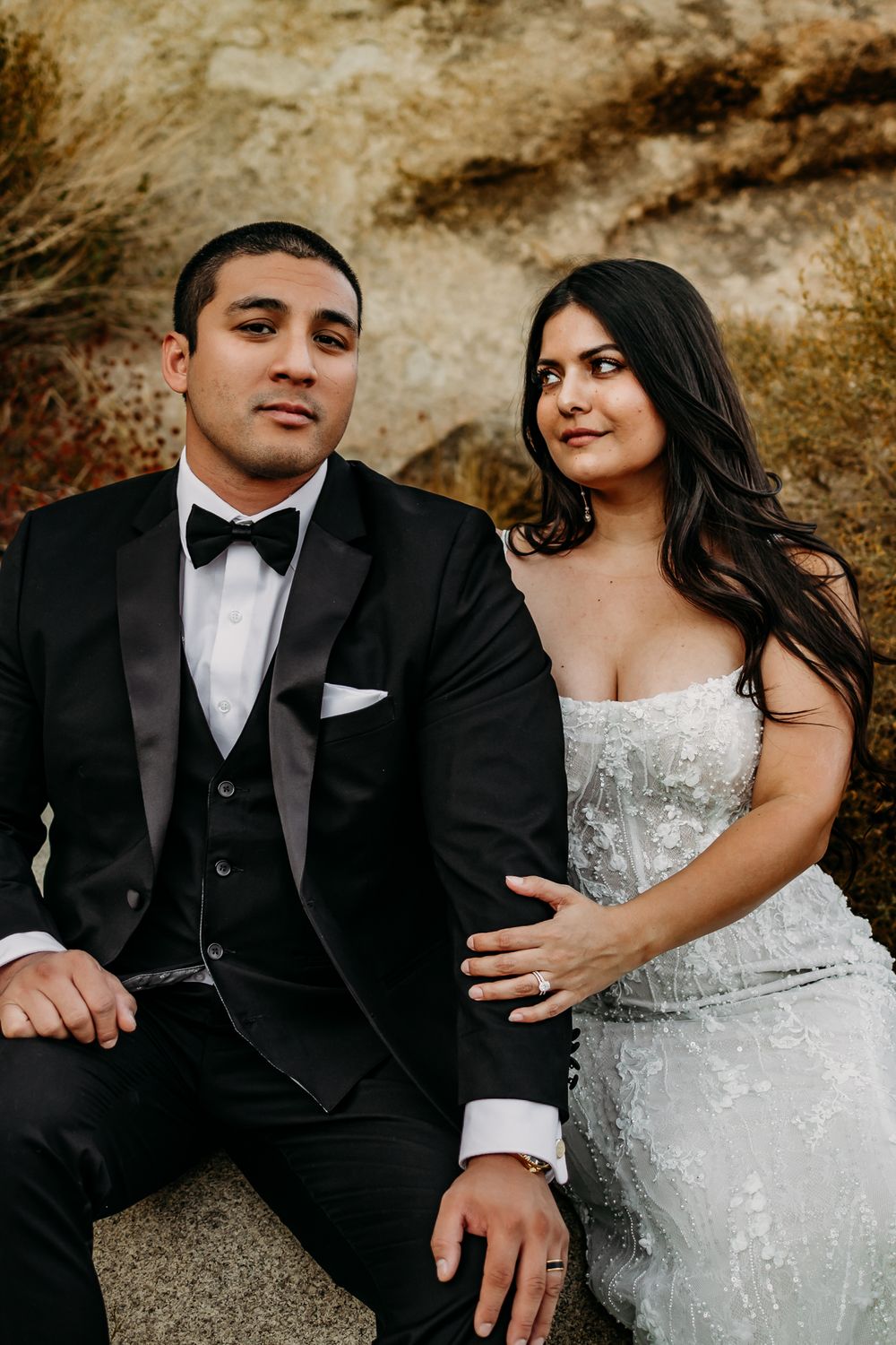 Elegant wedding couple in black tuxedo and beaded white gown share loving glances.
