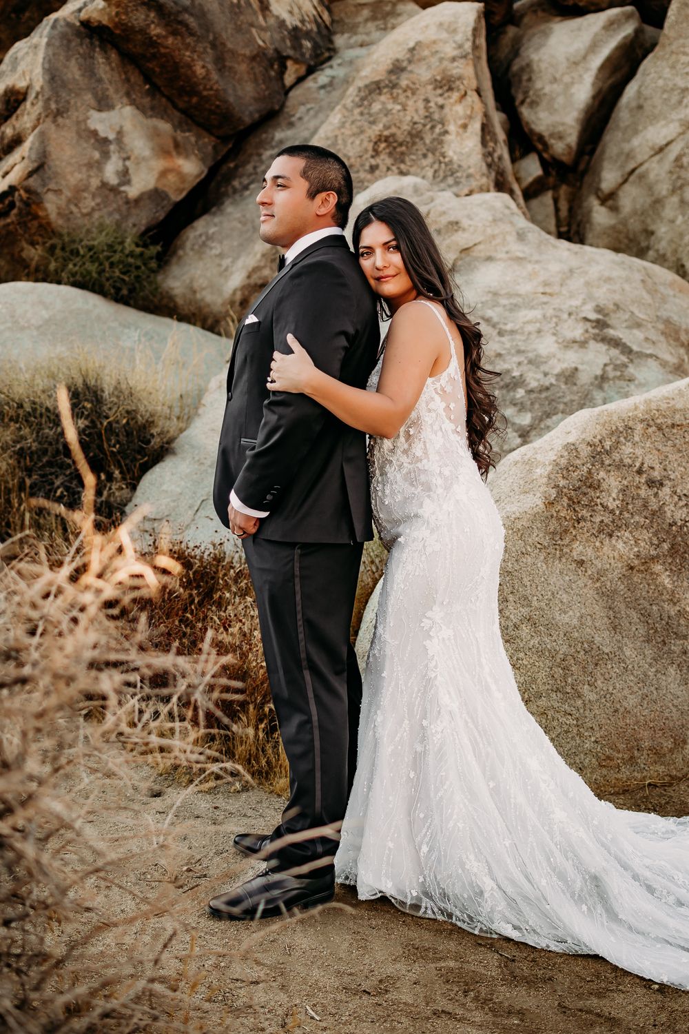 Newlyweds share tender moments while posing among dramatic rock formations.