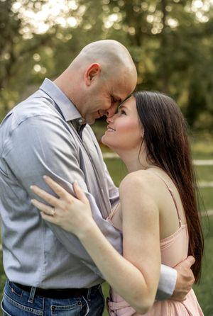 A couple shares an intimate kiss in a park setting with soft natural lighting.