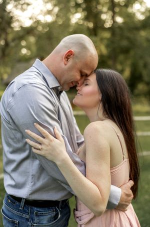 A couple embraces tenderly in a park during sunset with bokeh lighting effects.