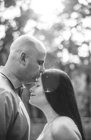 A couple shares a tender moment in black and white photography with dreamy bokeh background effects.