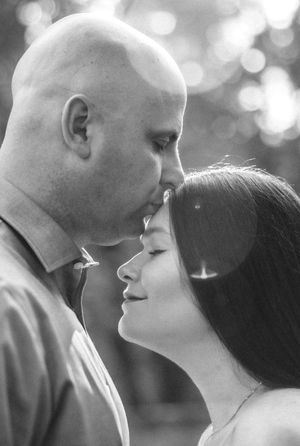 Black and white portrait series capturing intimate moments between a couple against blurred natural lighting.