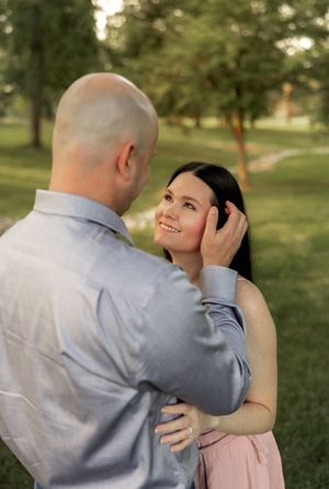 A tender moment between a couple during an outdoor photo session in a park.