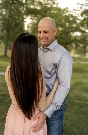 A couple sharing affectionate moments during a sunset photoshoot in a park setting.