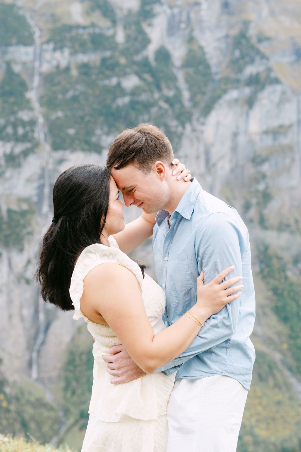 A romantic couple embraces against a backdrop of majestic mountain cliffs during an intimate proposal photoshoot in Mürren.