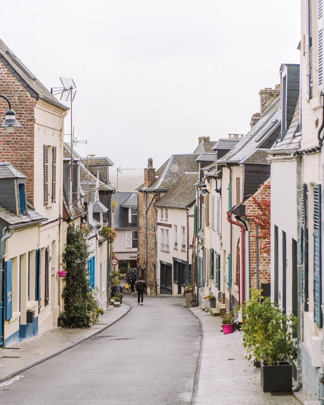 Quiet European village street lined with stone houses and pastel buildings.