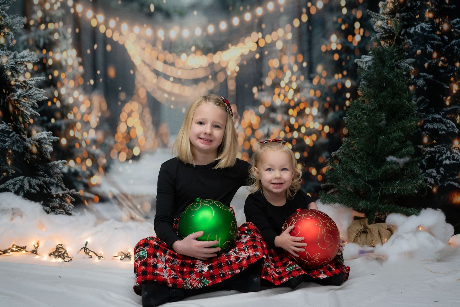 Winter themed photo setup with giant ornaments and twinkling lights in snowy scene.