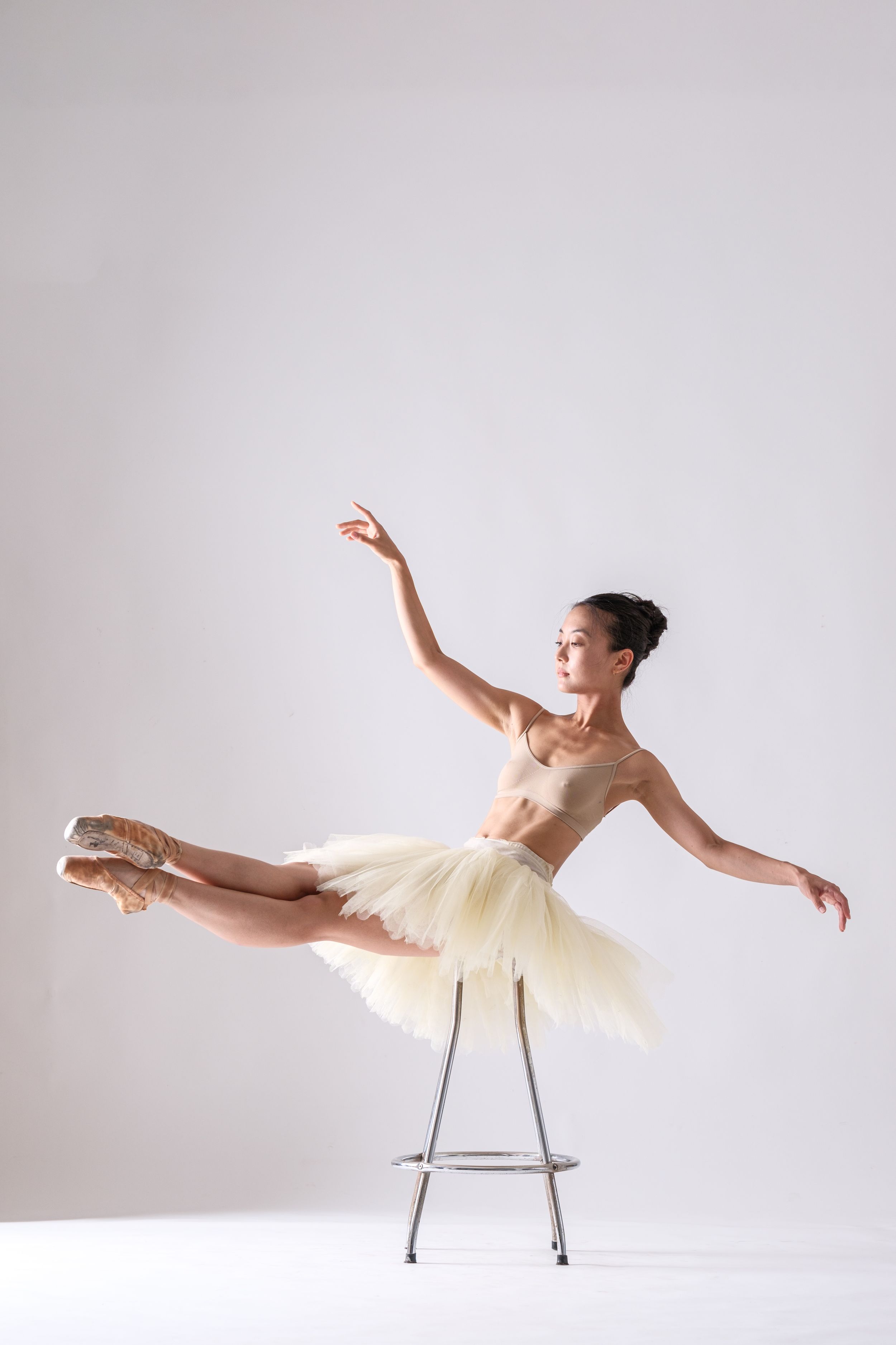 Dancer executes flowing movement sequence with chair in bright studio space.