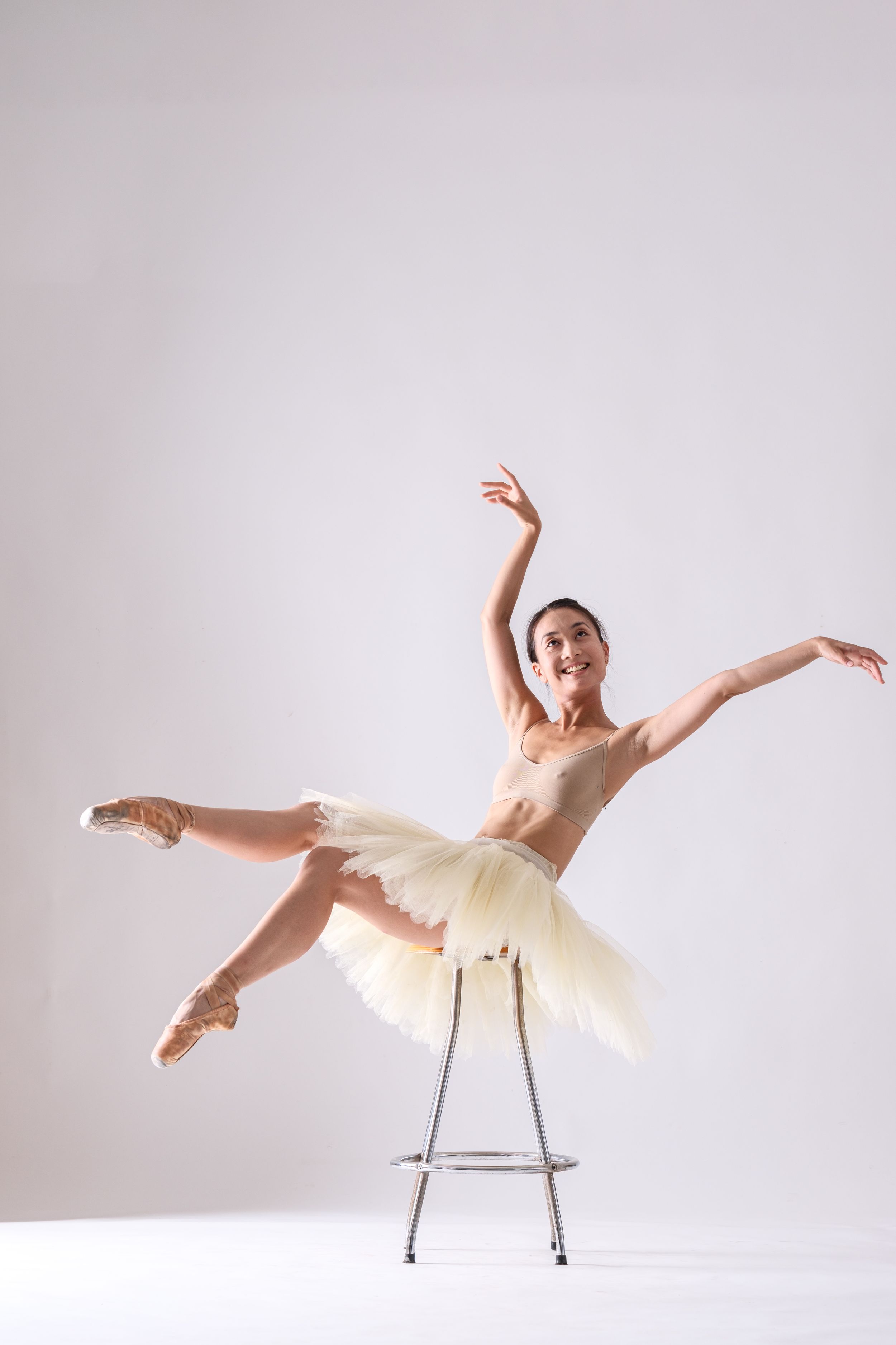 Contemporary dance performance featuring graceful movements with stool in minimalist setting.