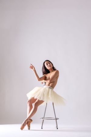 Artistic dance performance showing fluid motion and balance using chair prop in white studio.