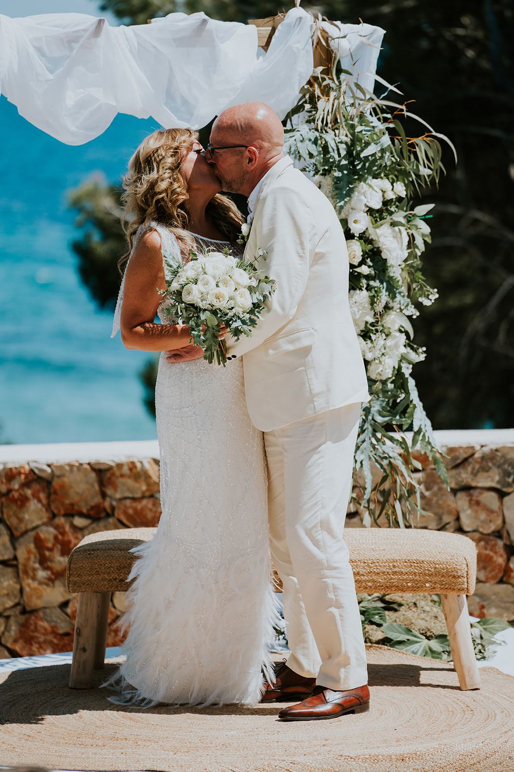 A romantic wedding moment captured against a stunning blue ocean backdrop.