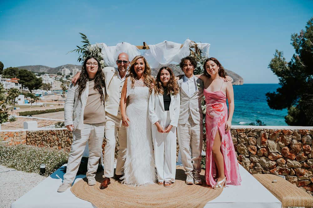 Wedding party poses together on coastal terrace with Mediterranean views.