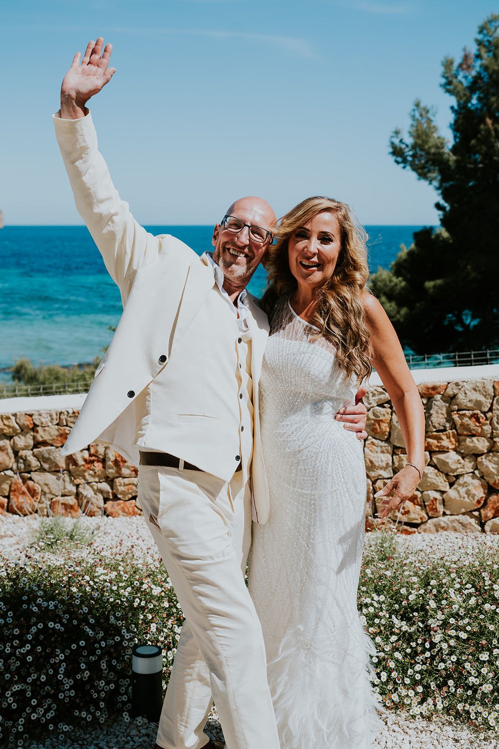 Joyful couple celebrates on their wedding day with Mediterranean Sea views.