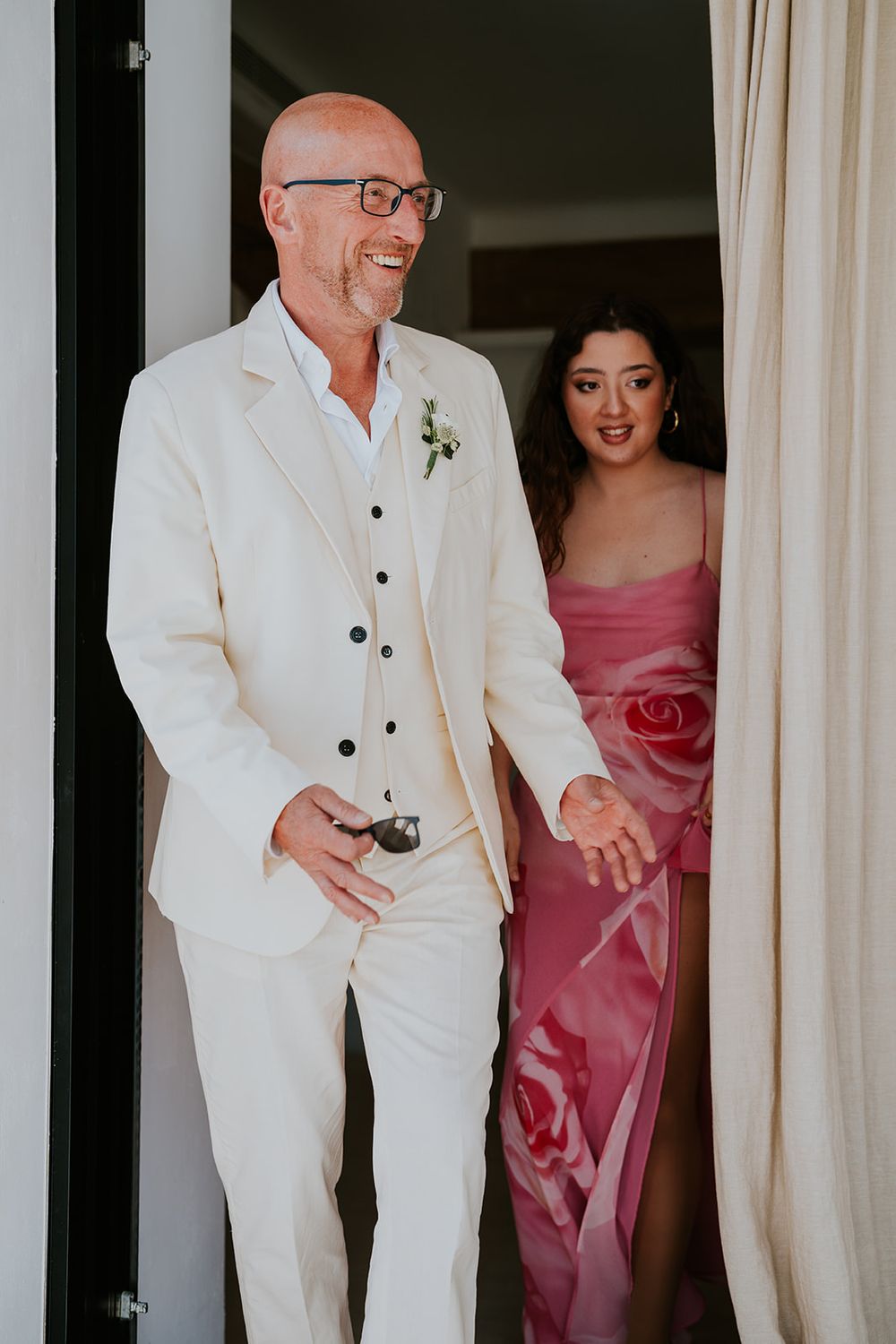 A wedding scene showing formal attire against a doorway with white and pink color scheme.