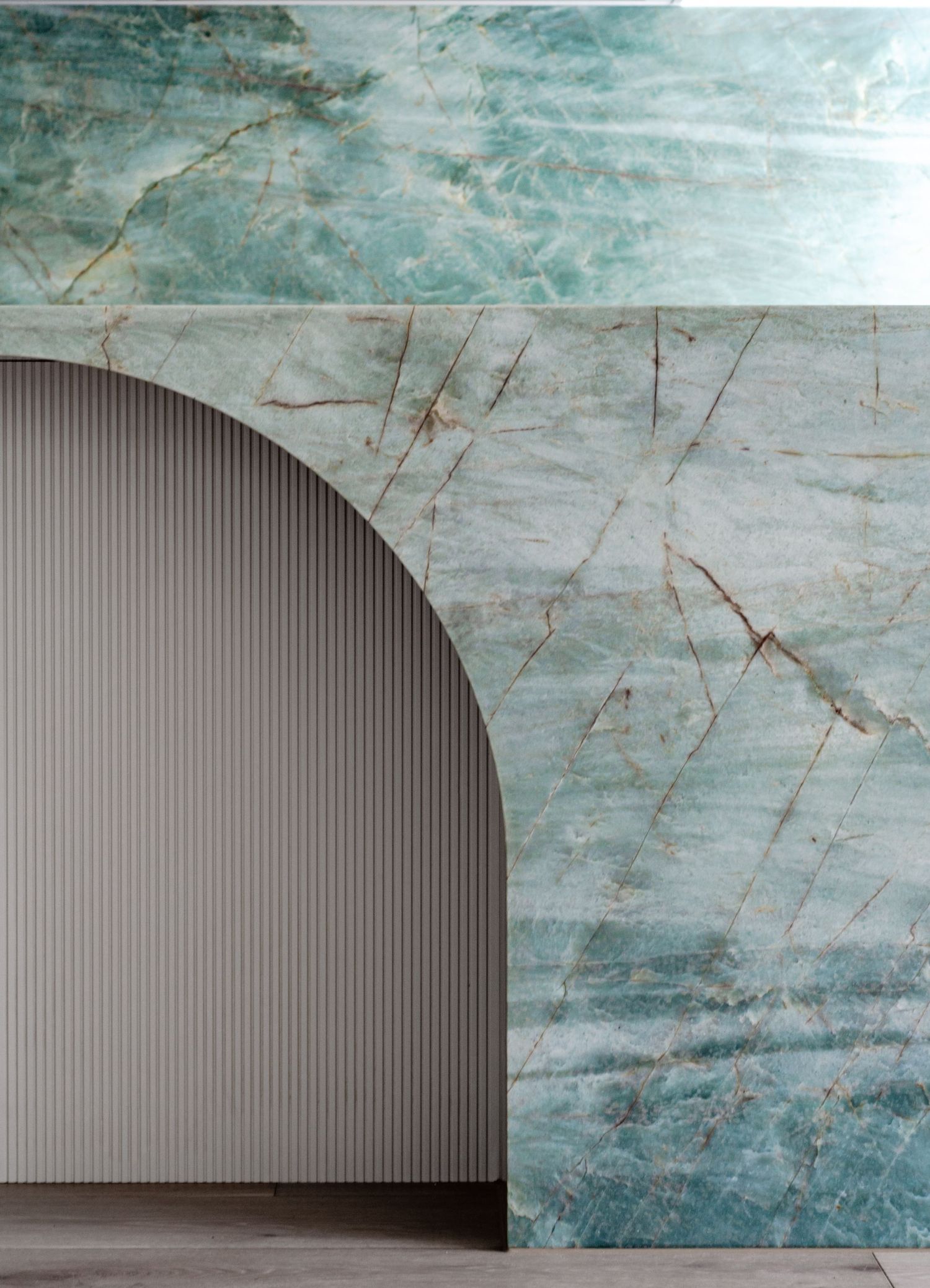 Architectural detail of turquoise marble wall with curved archway and vertical ribbed panel design.
