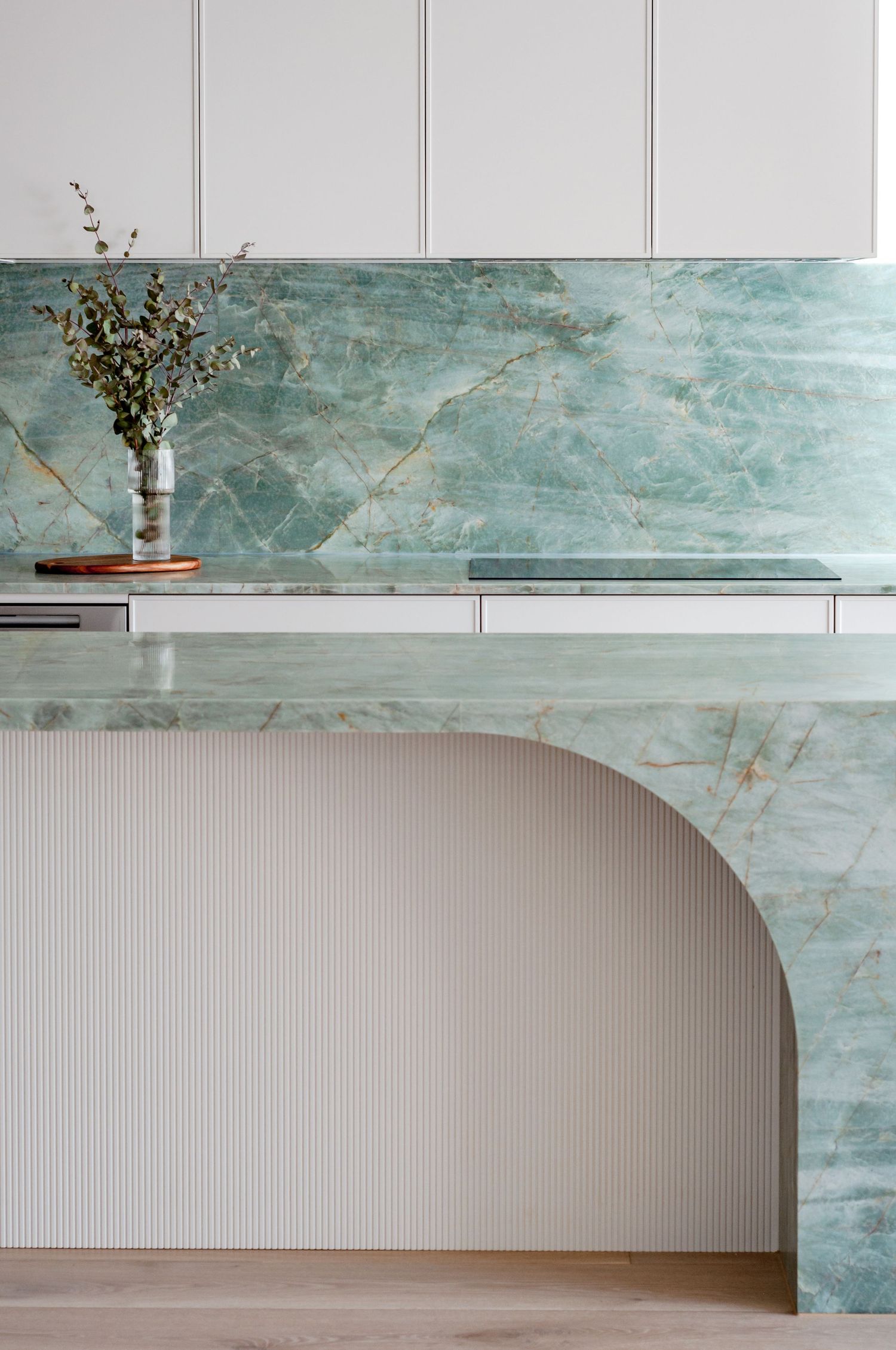 Modern kitchen design featuring mint green marble backsplash and curved archway detail.