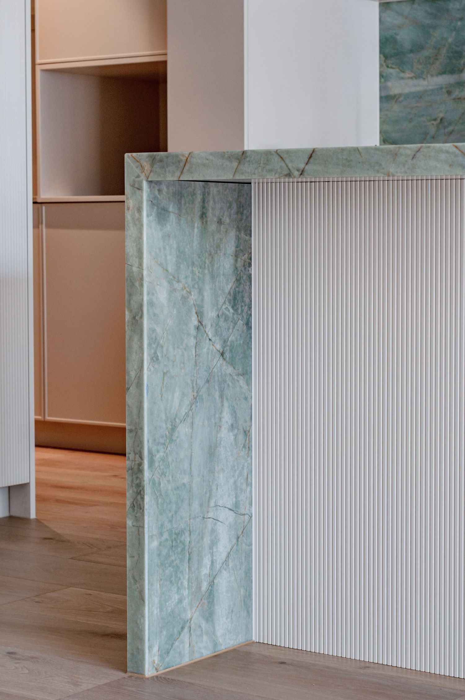 Close-up of mint green marble and white ribbed panel intersection in kitchen design.