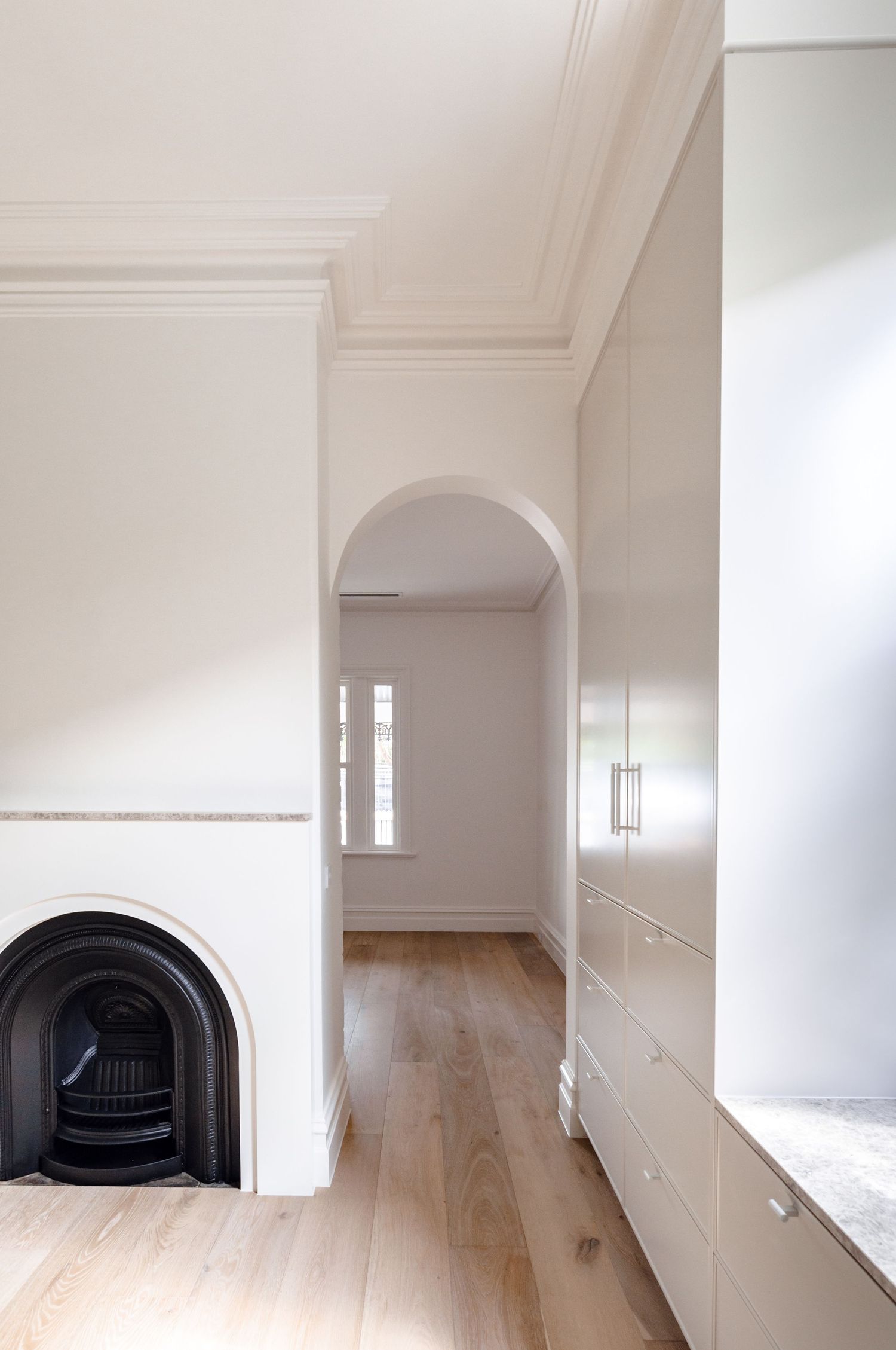 Classic interior with ornate fireplace, arched doorway, and built-in storage along hallway.