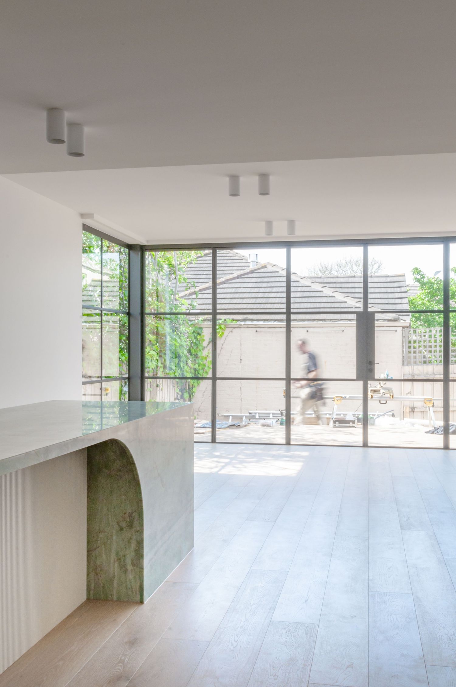 Minimalist room with floor-to-ceiling windows, track lighting, and curved architectural detail.