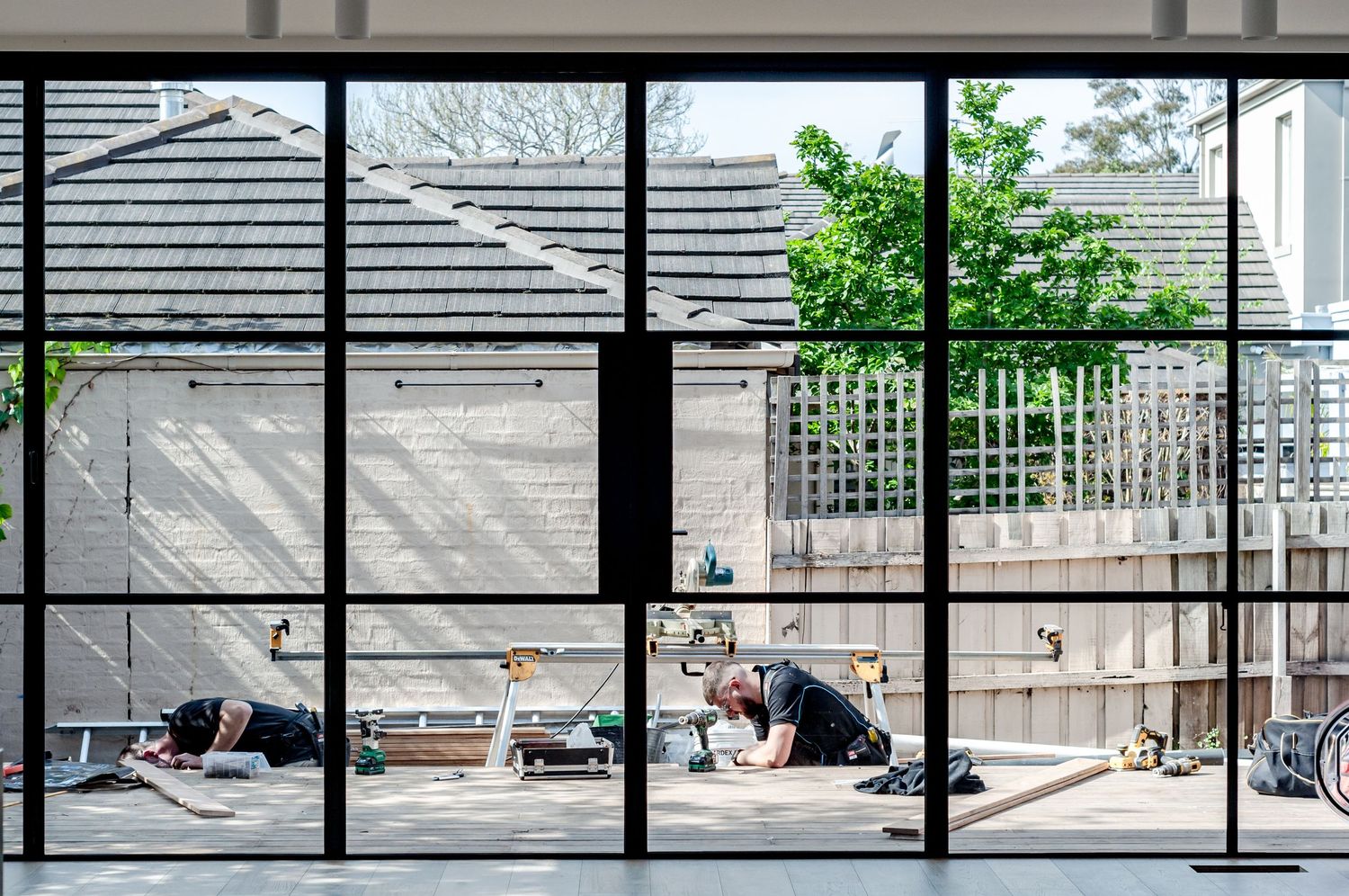 Large glass windows overlook outdoor patio space with contemporary landscaping.