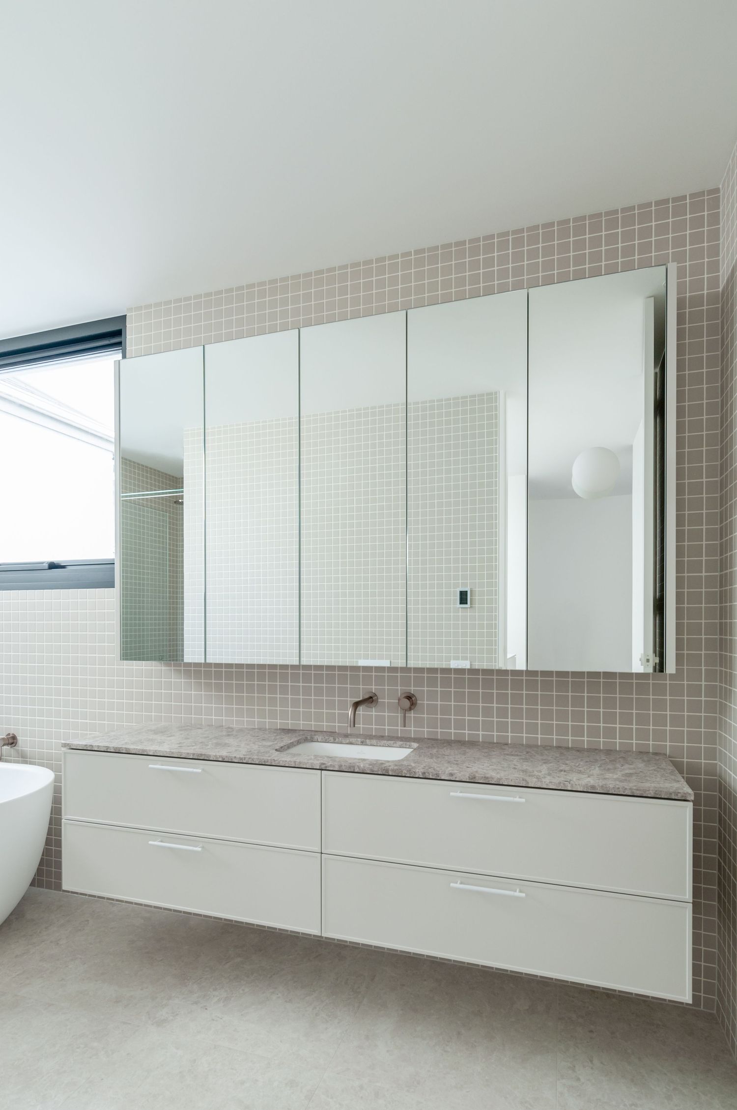 Contemporary bathroom featuring floating vanity, large mirror cabinet, and neutral tiled walls.