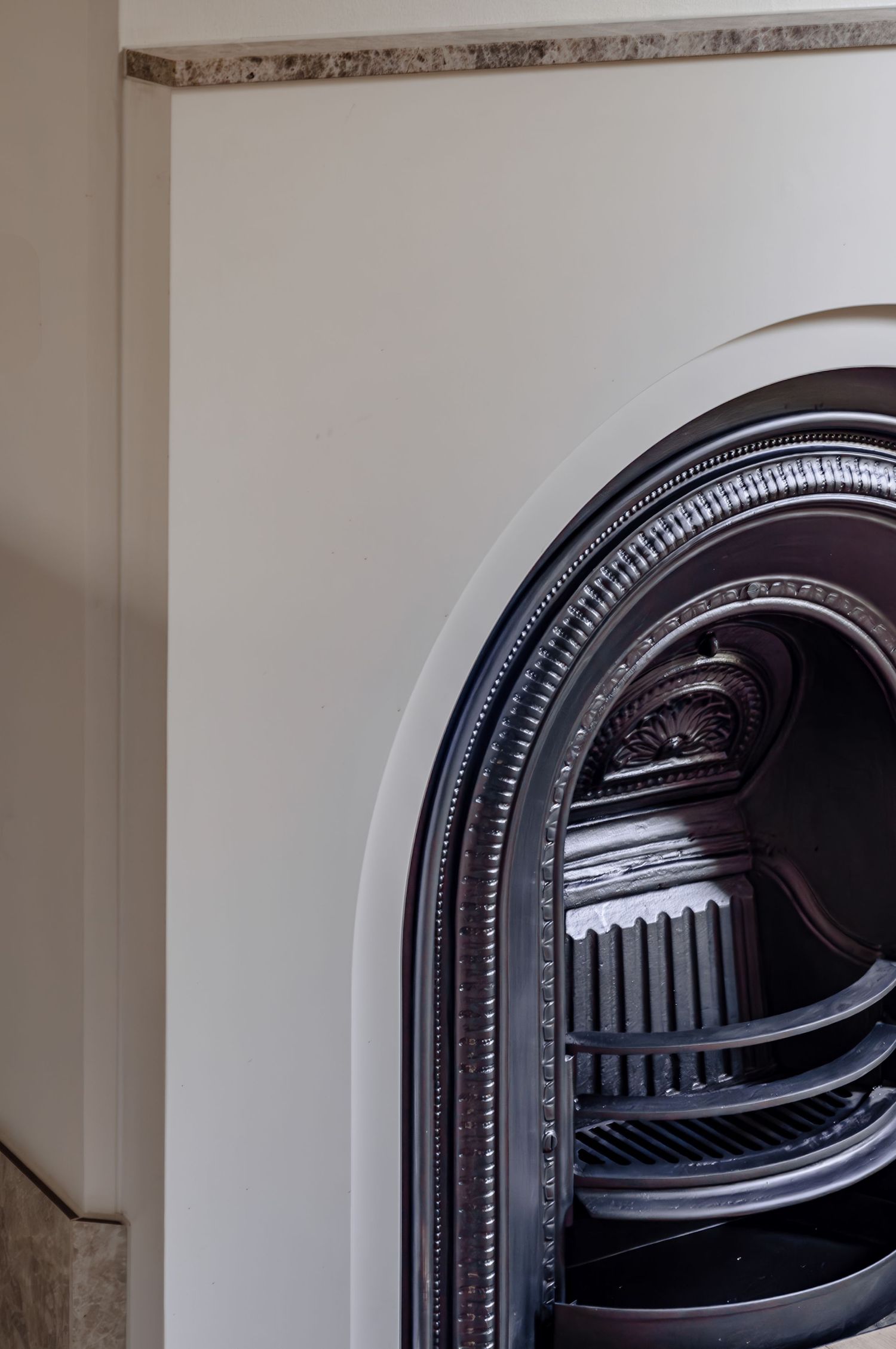Close-up of ornate curved black Victorian fireplace insert with decorative arch details.