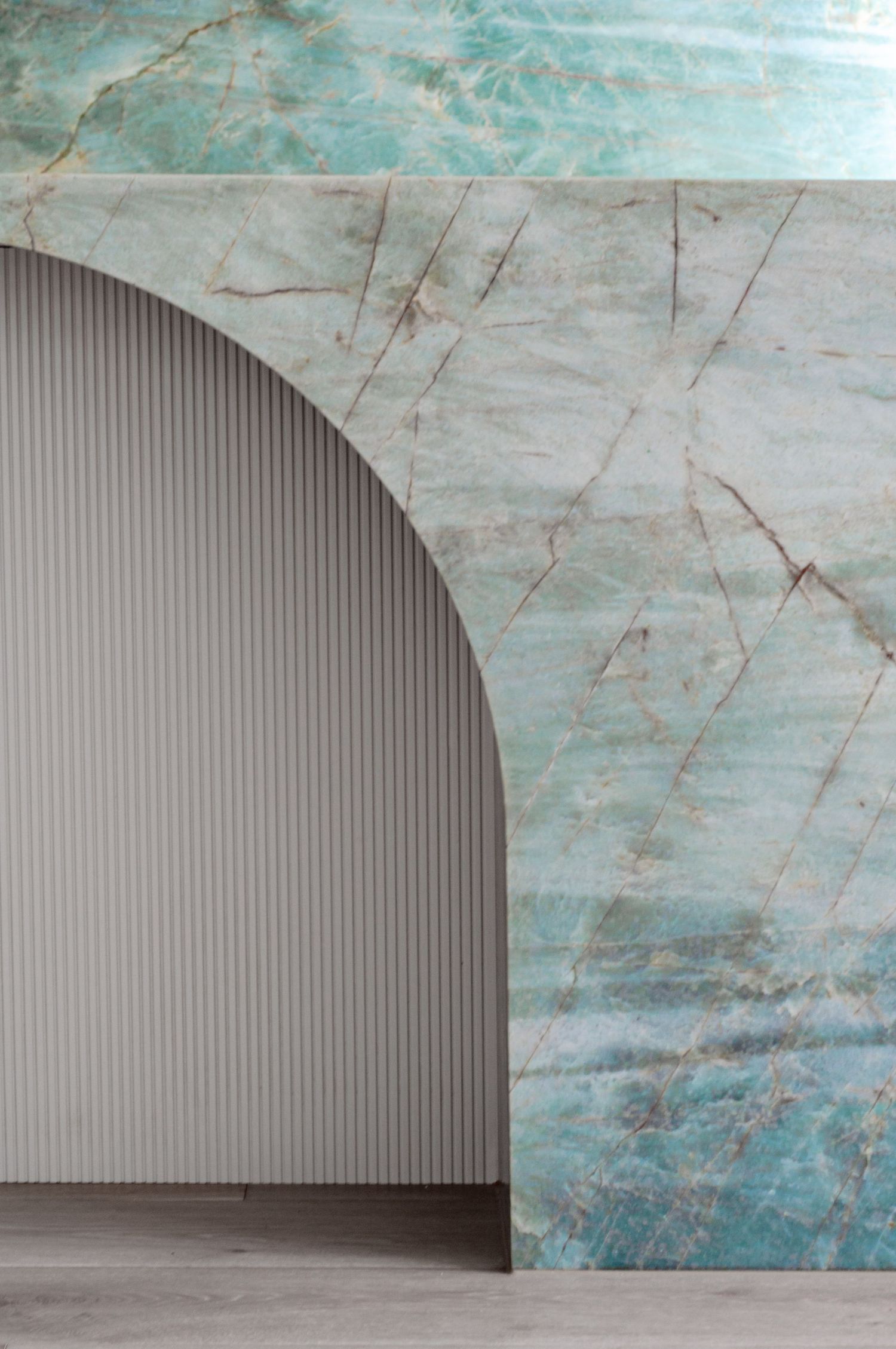 Architectural detail showing turquoise marble wall with curved archway and ribbed panel texture.