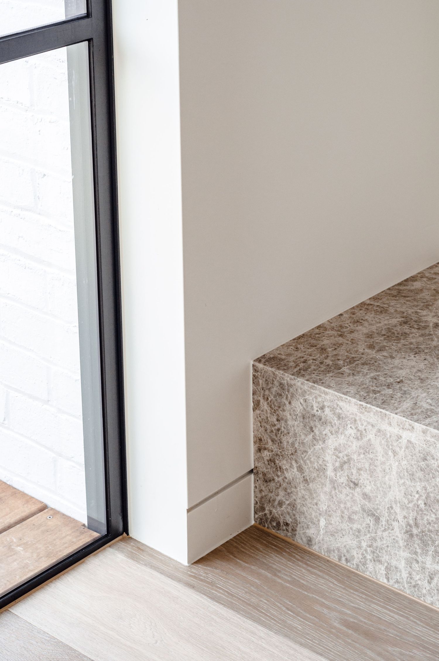 Modern interior corner showing floor-to-ceiling window and stone bench detail.