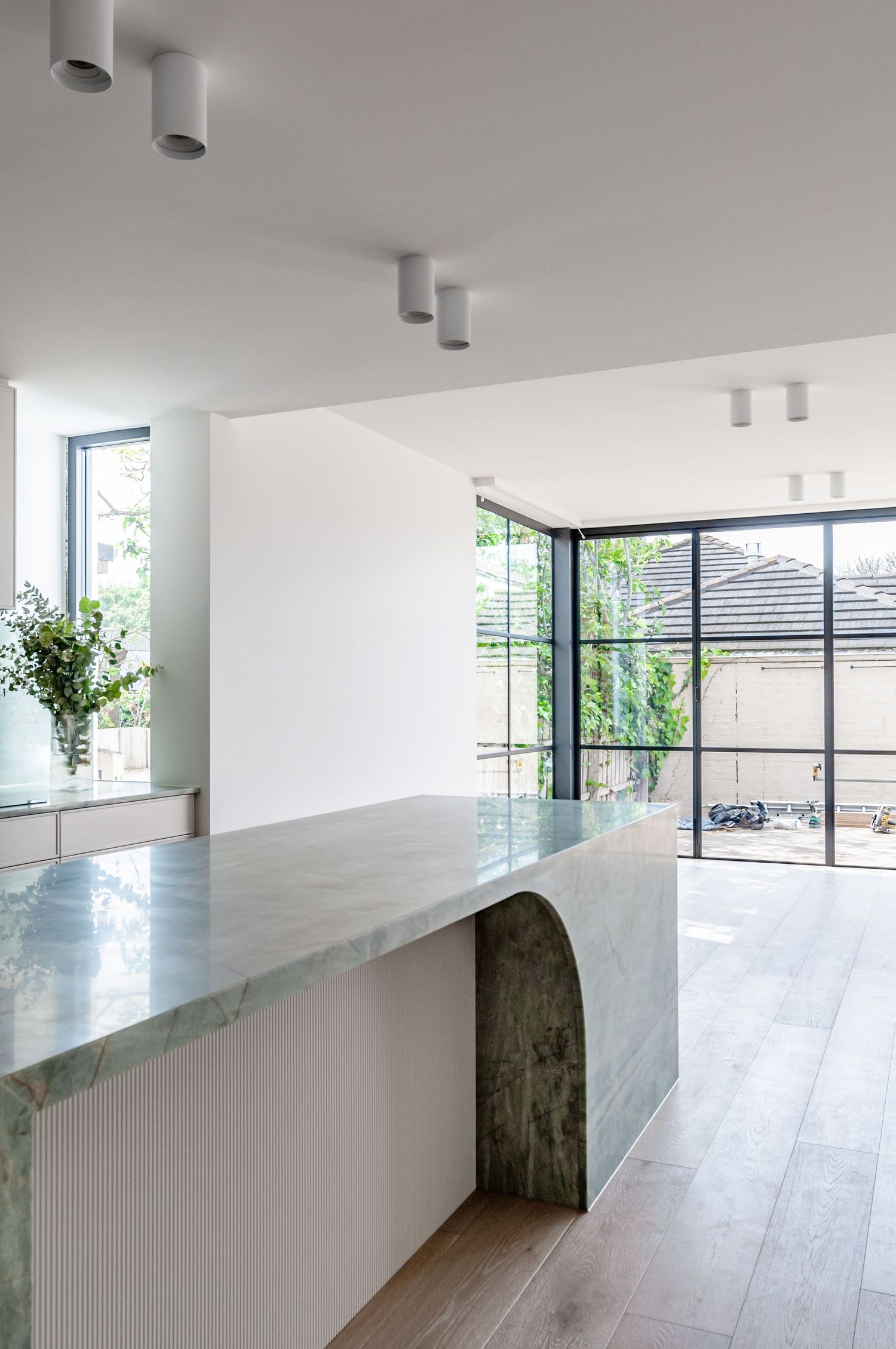 Bright open-concept kitchen with floor-to-ceiling windows and arched marble counter detail.