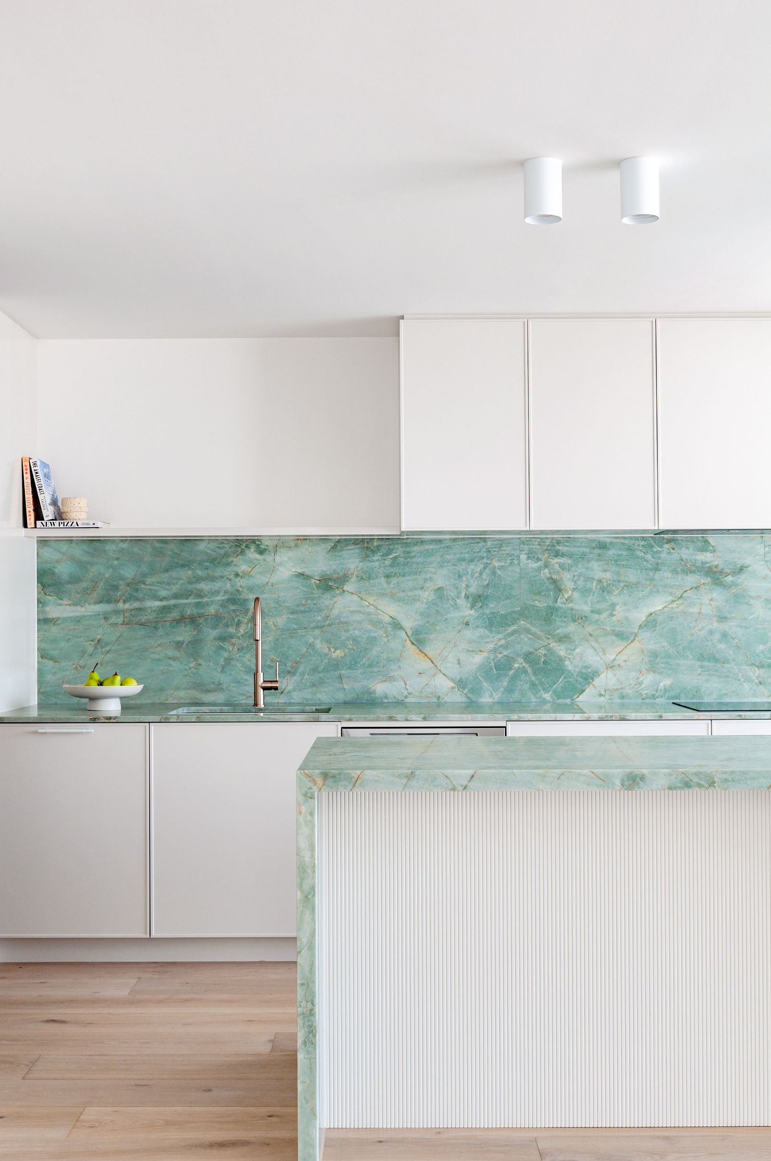 Modern kitchen featuring green marble countertops and backsplash with ribbed panel detail.