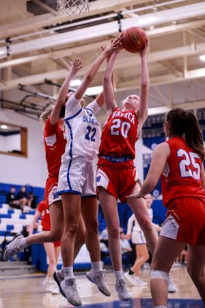 Basketball players jump for rebound during competitive game between red and blue teams.