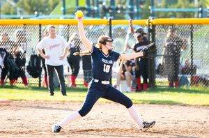 Softball players competing on a dirt field with yellow foul pole visible.