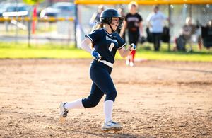 Softball players in motion on a dirt field during a competitive game.