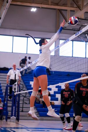 Dynamic volleyball action shot showing players leaping at the net during a competitive match.