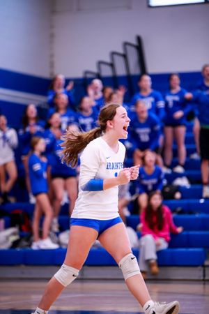 Players display athletic intensity during a competitive indoor volleyball match in a school gymnasium.