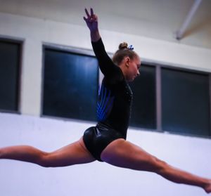 Gymnast performing a split leap during floor exercise routine.
