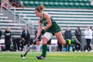 Field hockey players battle for ball possession during competitive match on turf field.