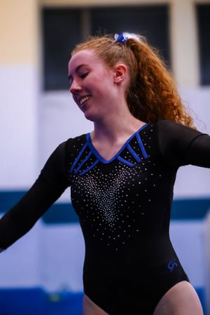 Gymnast performing artistic movements in sparkly black leotard during floor routine.