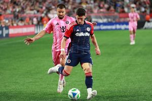 Soccer players in pink and navy uniforms compete for the ball during a match.